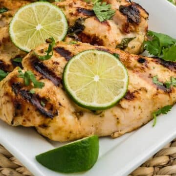 Coconut Lime Chicken marinade on grilled chicken breasts with slices of lime.