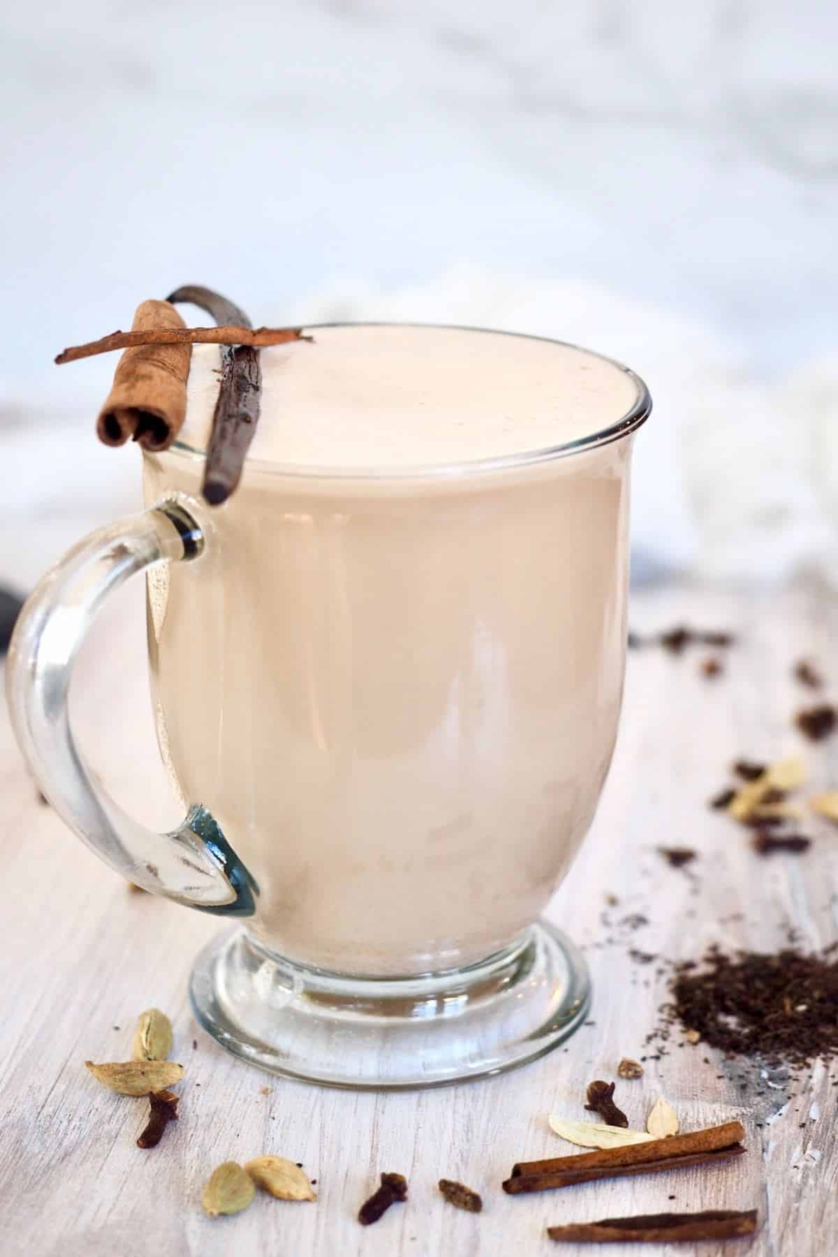 Starbucks chai tea latte in glass mug garnished with a cinnamon stick and a vanilla bean. 