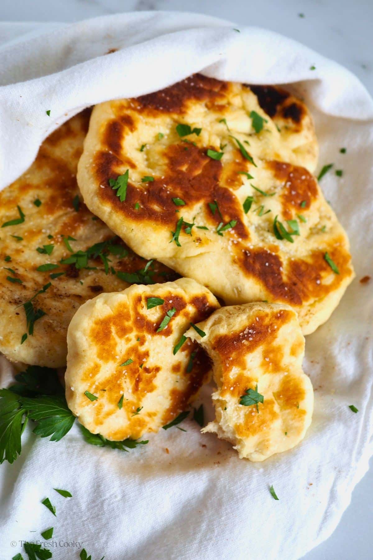 A torn piece of naan bread with others behind. 