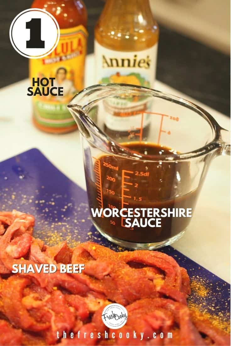 ingredient image with left to right, Cholula hot sauce, Annie's Worcestershire sauce, glass measuring cup with worcestershire sauce and thinly sliced steak seasoned on blue cutting board.