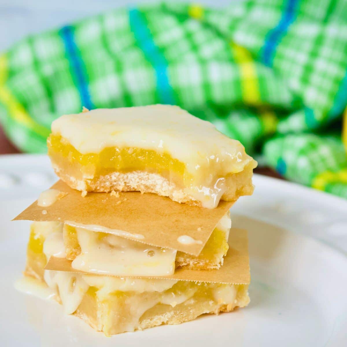 Three stacked old fashioned lemon squares with drippy frosting. 