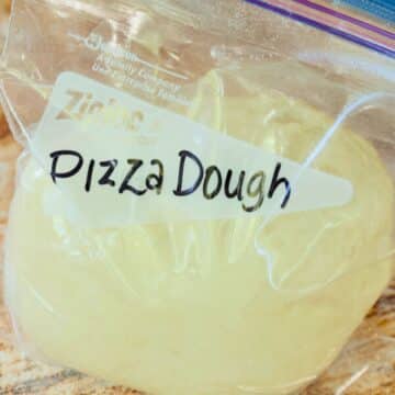 Pizza dough ball in a quart size baggie for freezing, with Pizza Dough written on baggie.