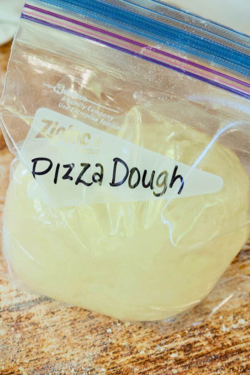Pizza dough ball in a quart size baggie for freezing, with Pizza Dough written on baggie.