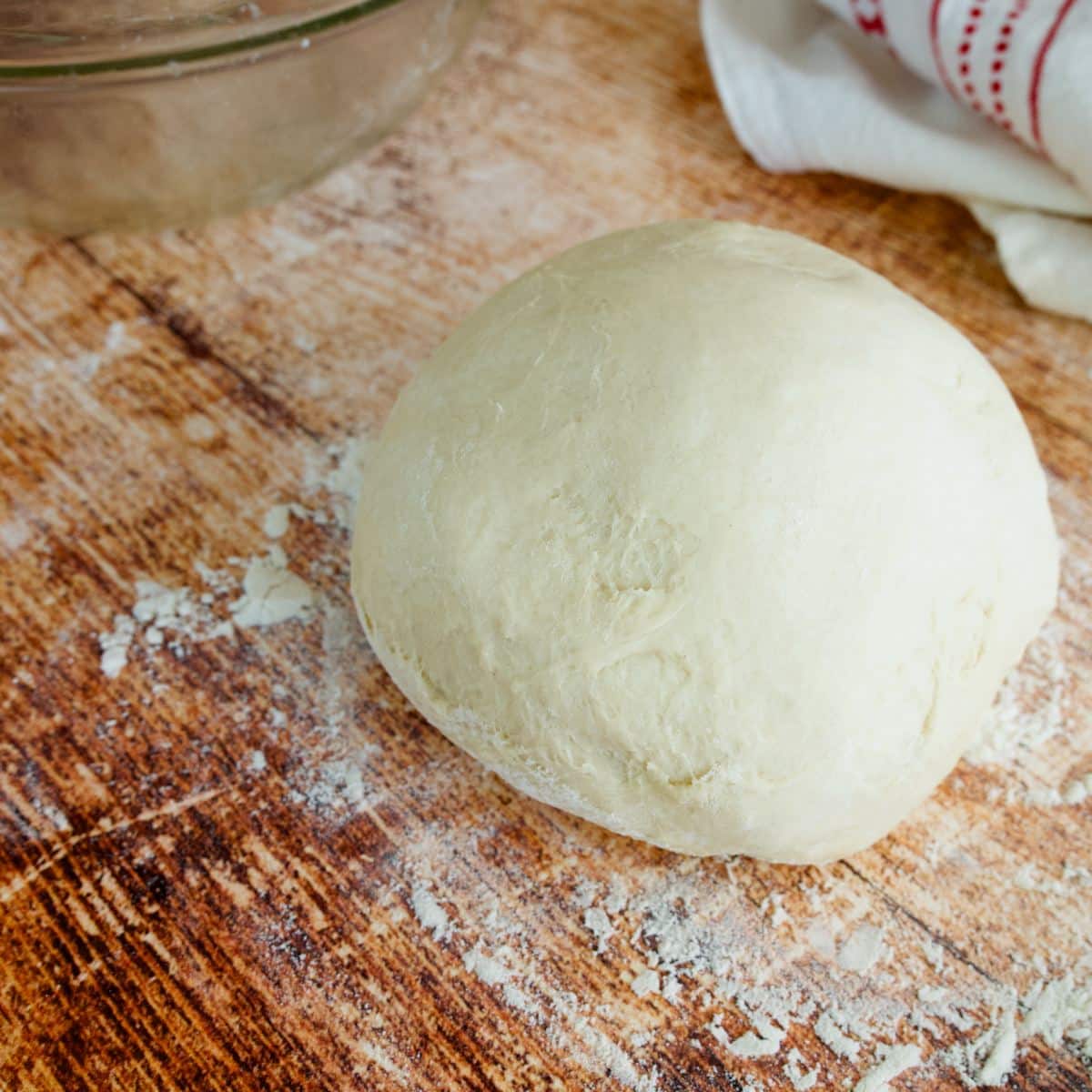 A ball of pizza dough on a floured surface. 
