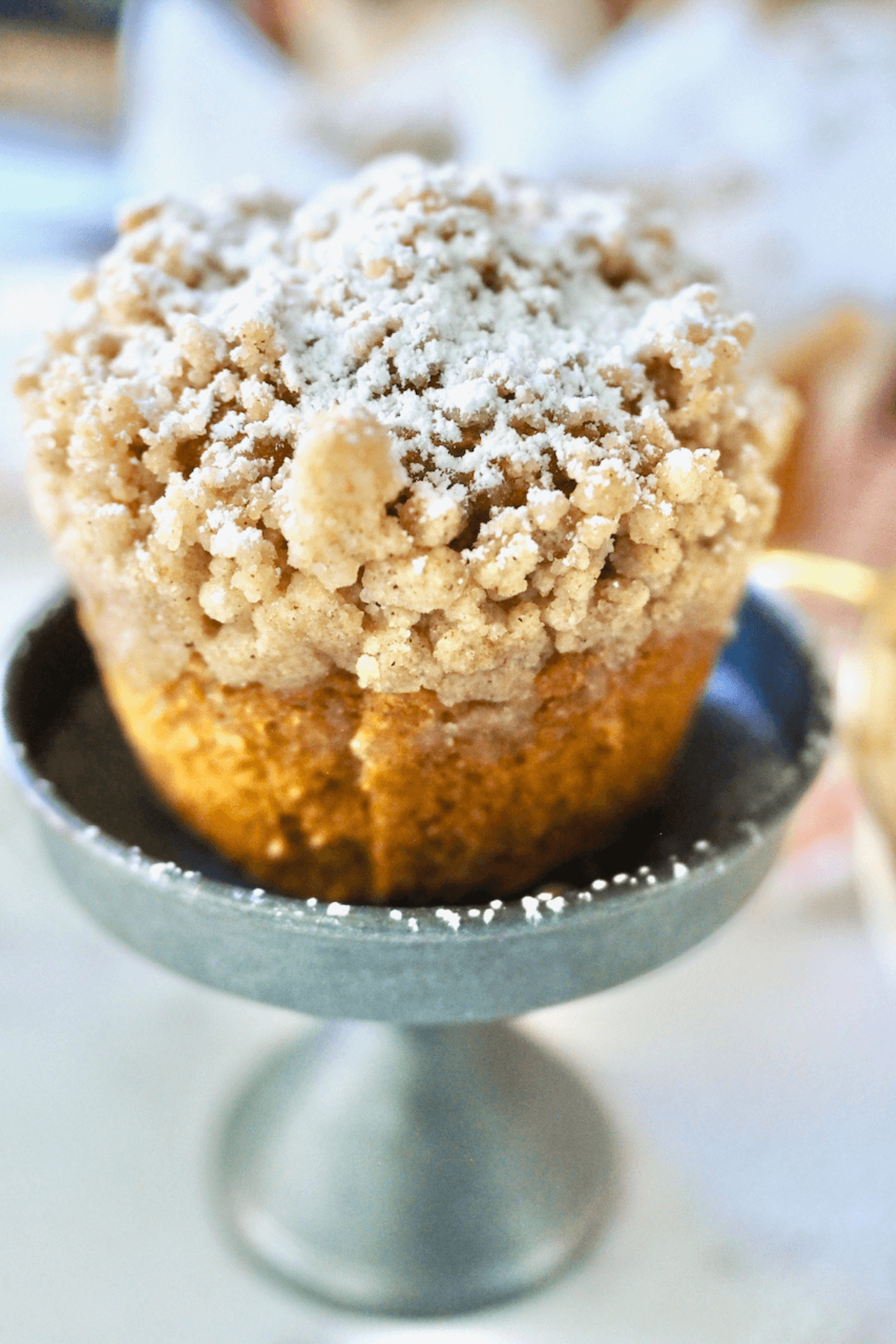 Pumpkin streusel topped muffin on a pedestal stand. 