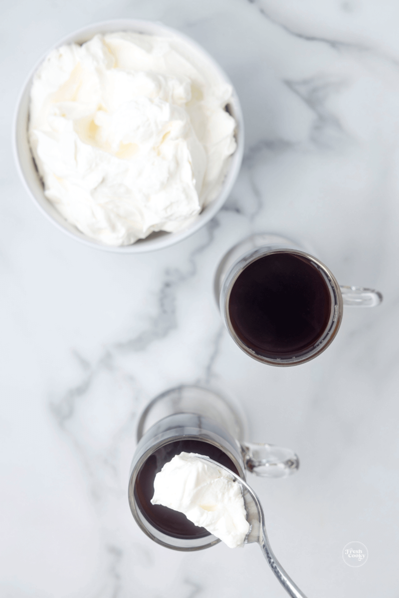 https://www.thefreshcooky.com/wp-content/uploads/2023/02/spoon-adding-dollup-of-whipped-cream-to-coffee-800x1200.png