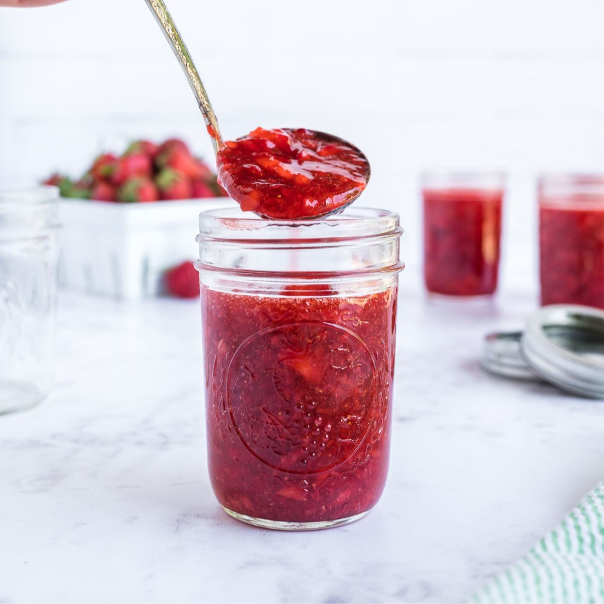 Scooping low sugar freezer jam into a jelly jar. 
