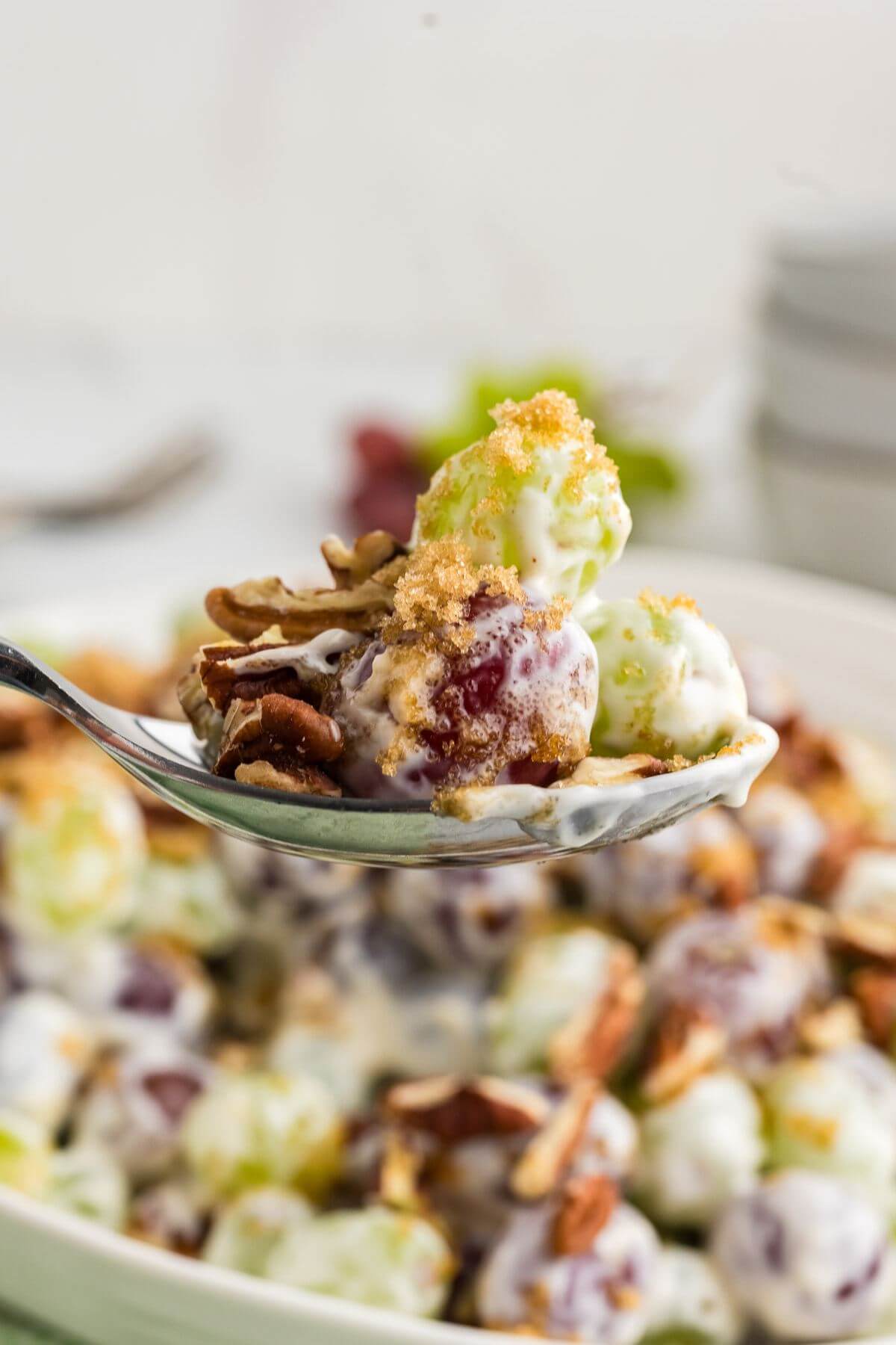 A spoonful of grape salad with crunchy brown sugar and pecans.
