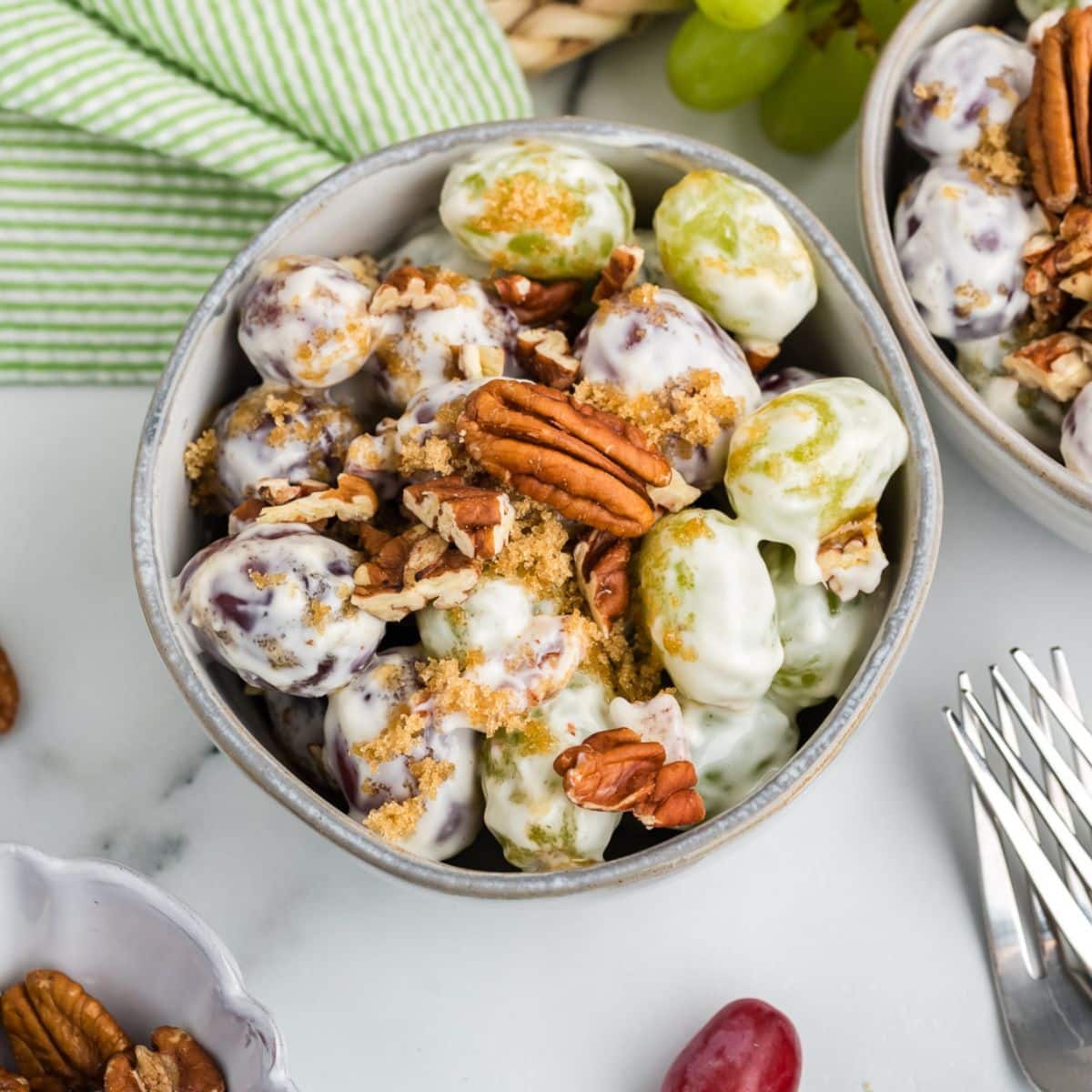 A serving of creamy Chicken Salad Chick Grape Salad topped with chopped pecans and light brown sugar. 