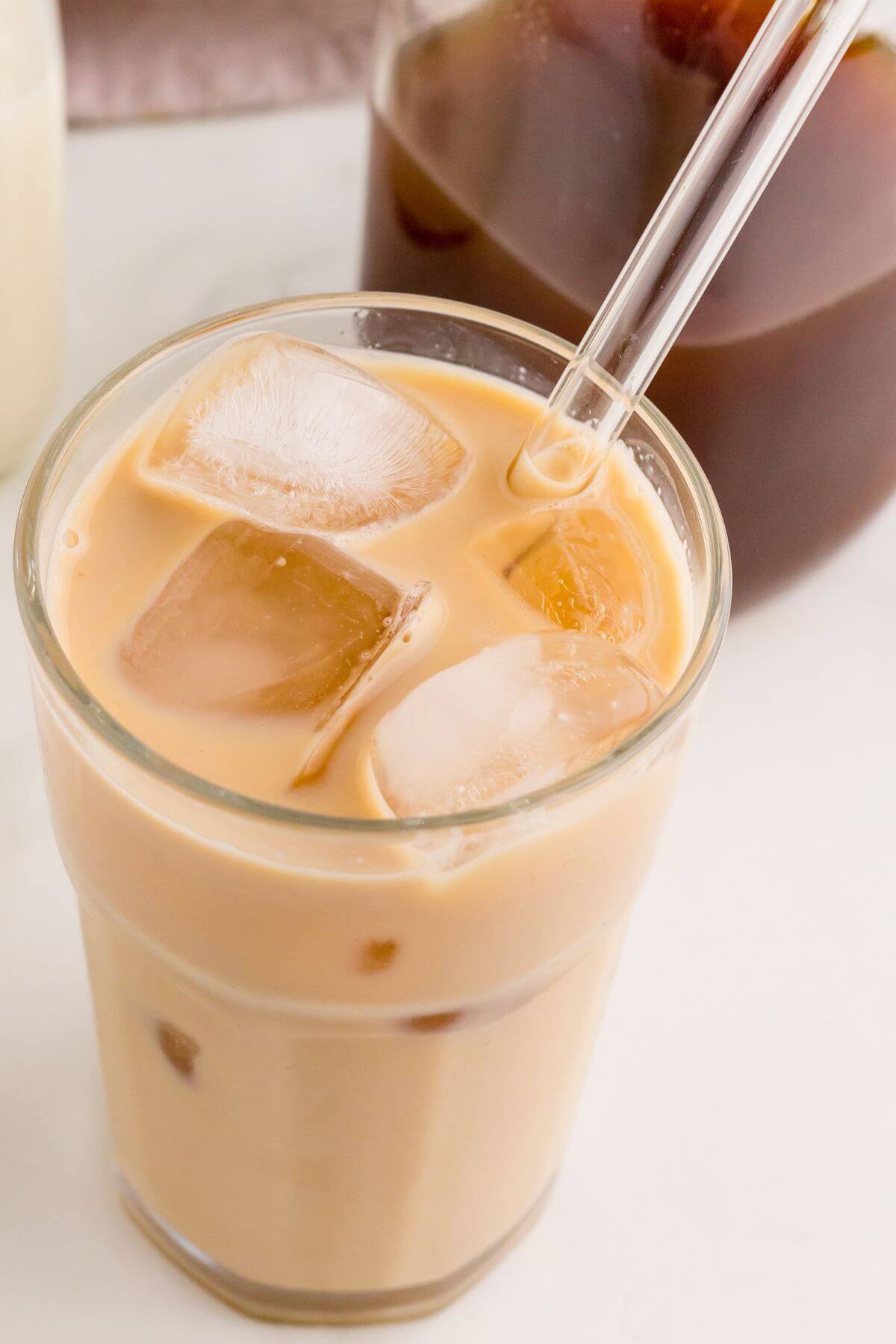Light brown chai and milk is blended together for a smooth drink in a glass with straw.