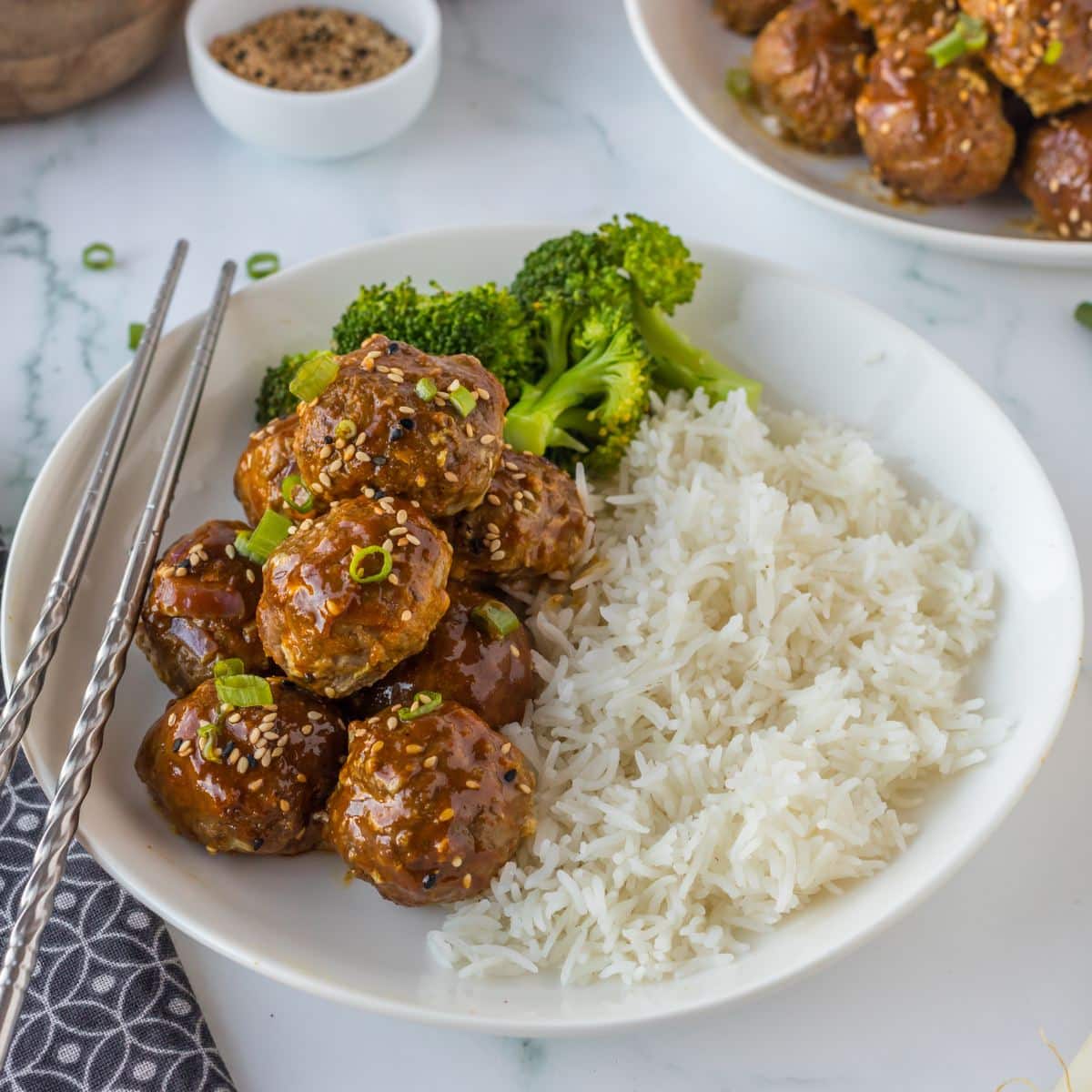 A bowl with Korean meatballs with a sticky yummy sauce, over white rice with steamed broccoli. 