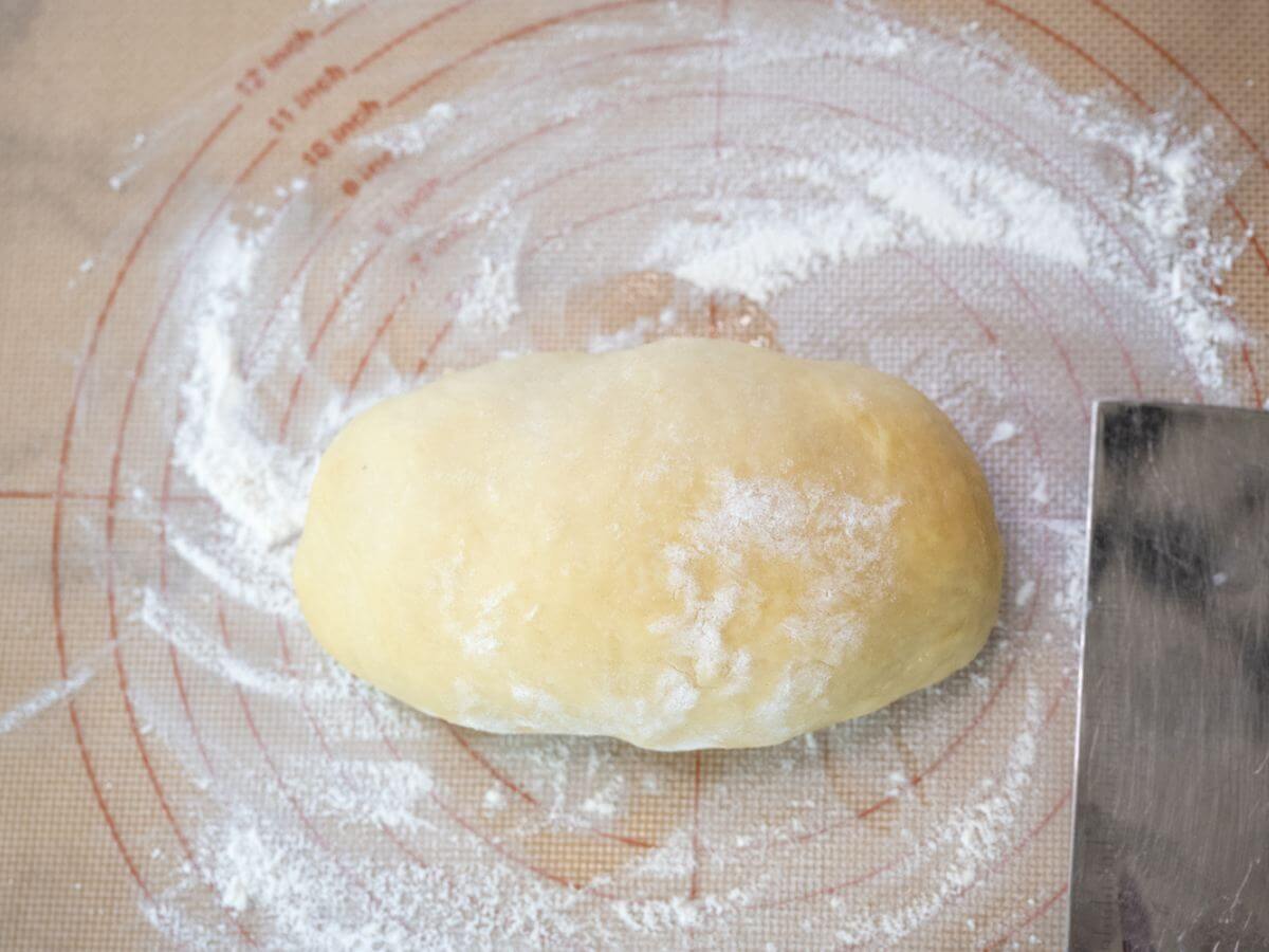 A disc of dough sits on a floured surface.