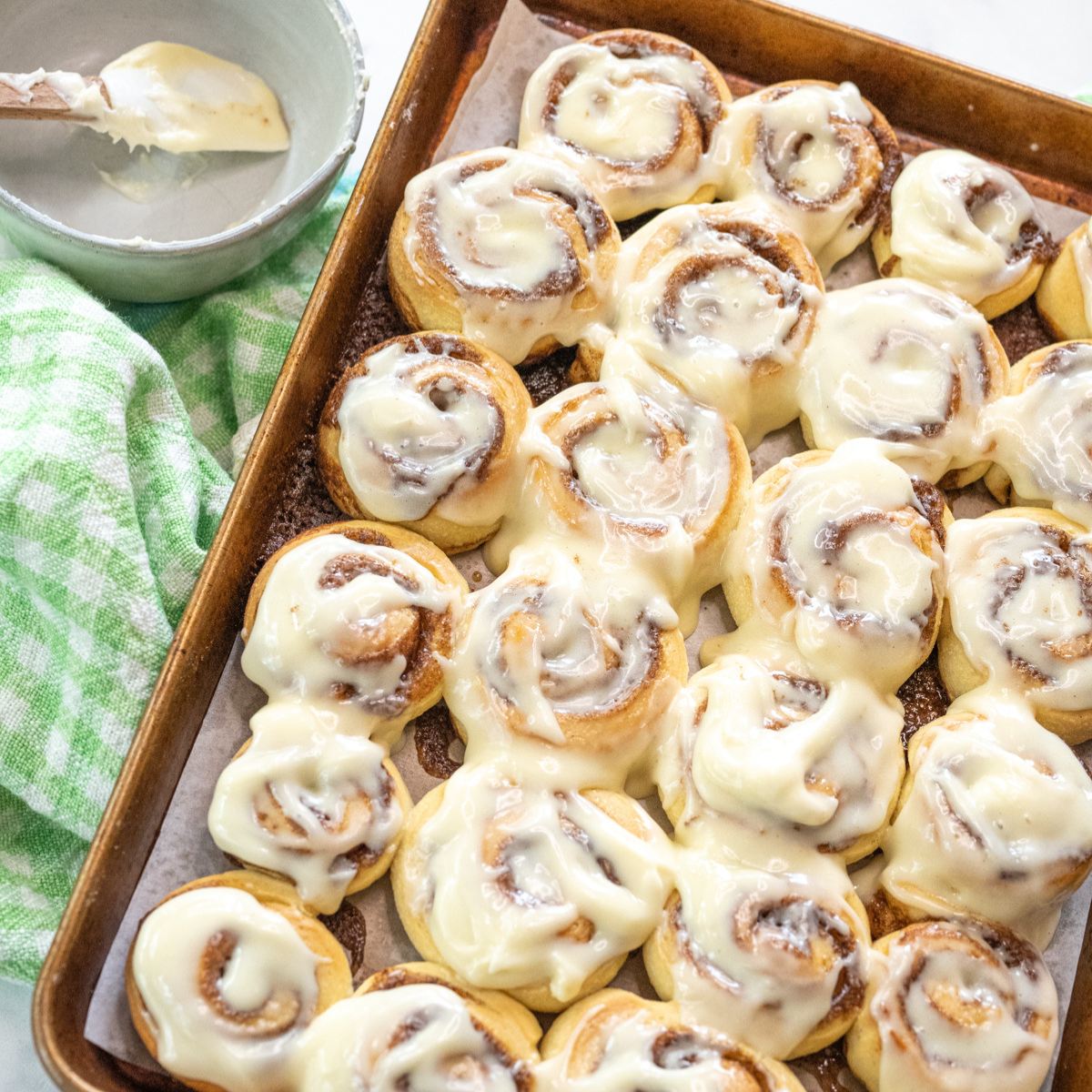 A pan filled with mini cinnamon rolls slathered with a cream cheese frosting.
