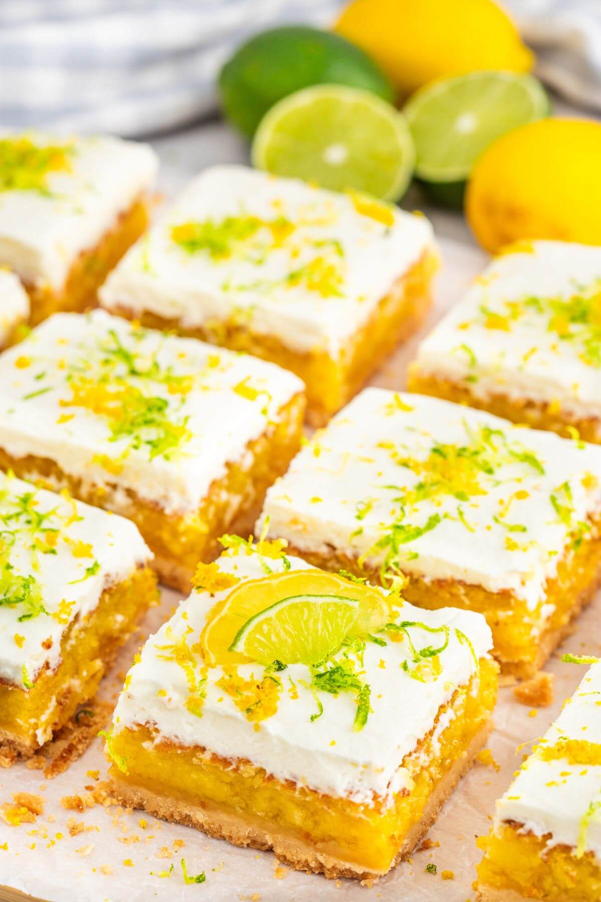 Neat rows of lemon lime squares rest in front of whole, fresh citrus fruits.