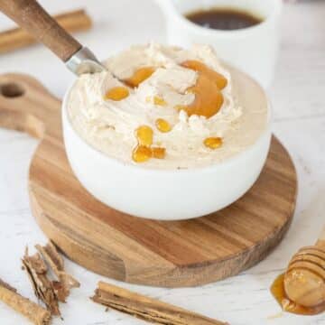 Whipped honey butter with cinnamon sticks and honey nearby.