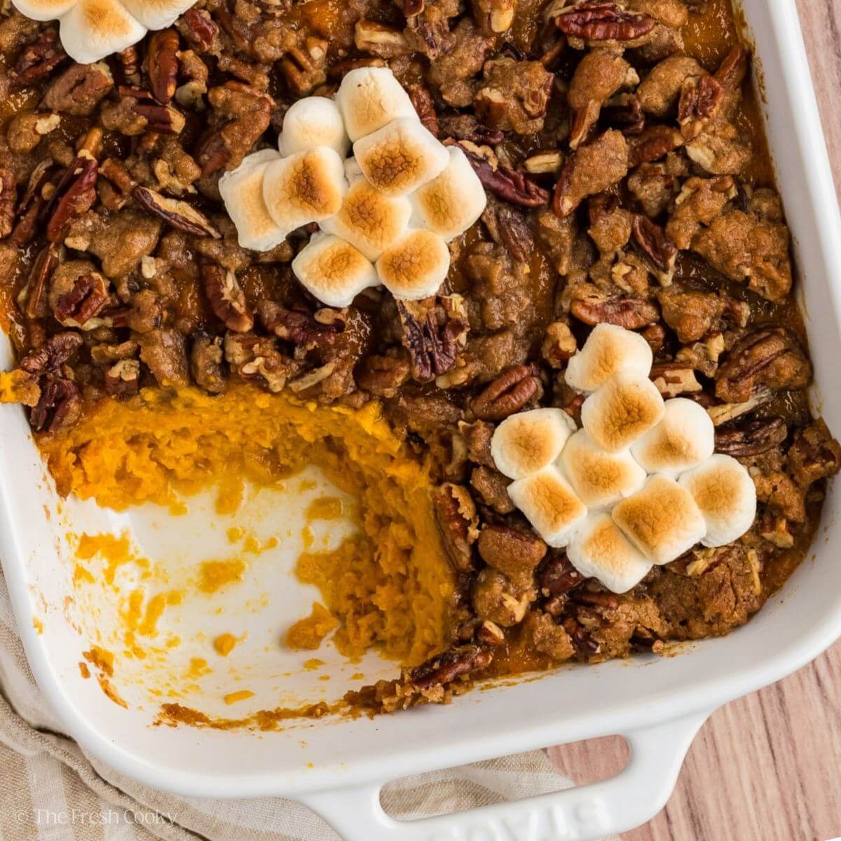 Sweet potato casserole in a baking dish with a portion missing from the dish.