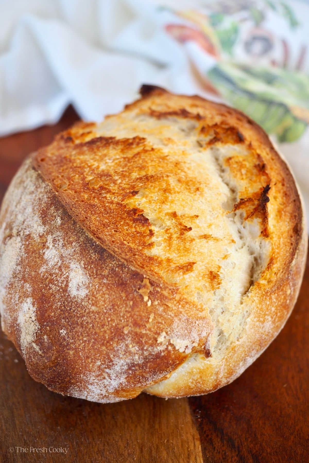 A golden beautiful loaf of sourdough bread on a cutting board.