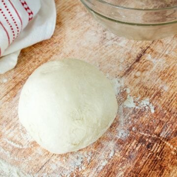 Easy and Quick Pizza Dough Recipe with dough on floured surface square.